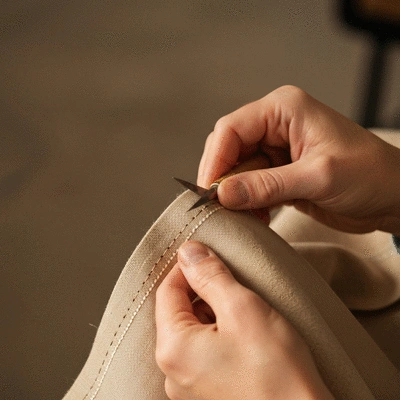 Close-up of hands expertly performing hand stitching on fabric, with perfectly even stitches visible, demonstrating high precision and consistency, in a well-lit crafting studio.